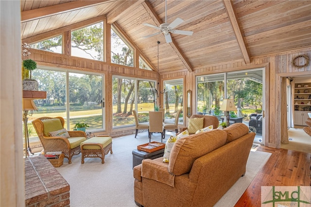 living area featuring beam ceiling, a healthy amount of sunlight, and wooden ceiling