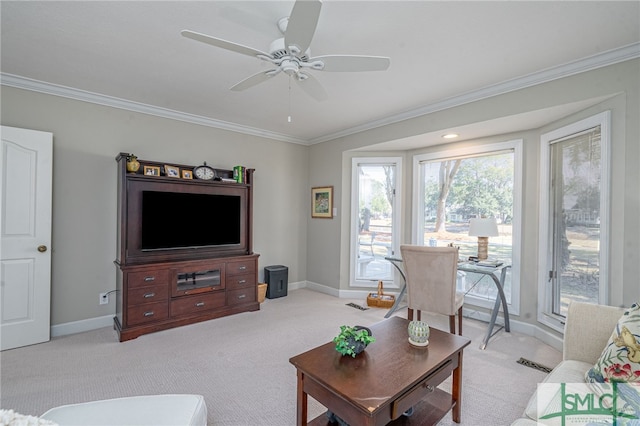 living room featuring baseboards, ornamental molding, a ceiling fan, and light colored carpet