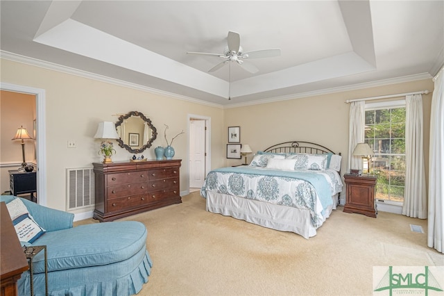 bedroom featuring a tray ceiling, visible vents, crown molding, and light carpet