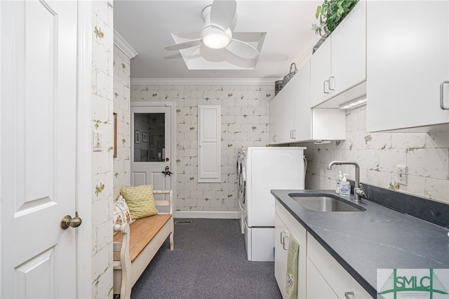 kitchen featuring washer and clothes dryer, ornamental molding, white cabinets, a sink, and ceiling fan