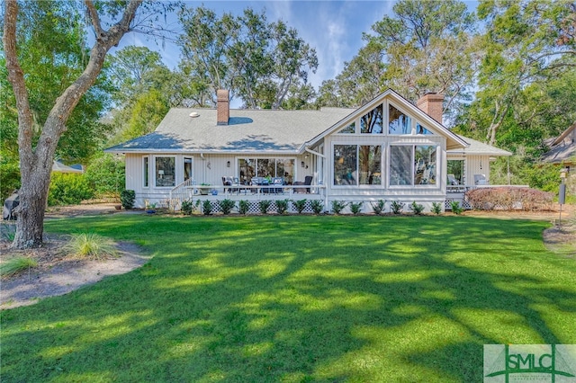 view of front facade featuring a shingled roof, a front yard, and a chimney