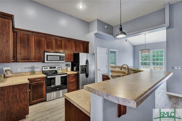 kitchen featuring pendant lighting, a center island with sink, light countertops, appliances with stainless steel finishes, and a sink