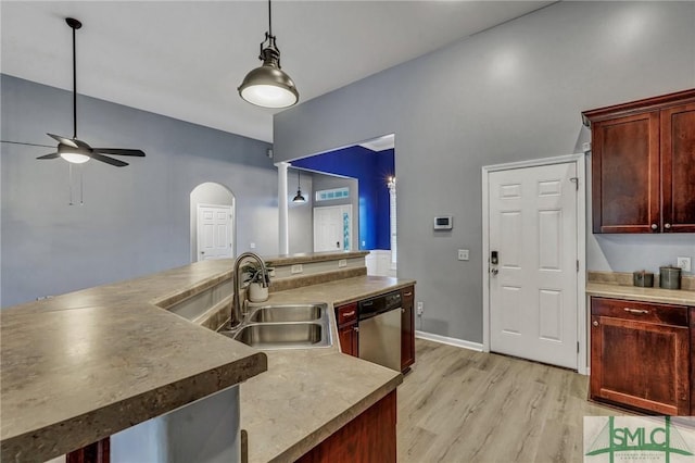 kitchen with reddish brown cabinets, arched walkways, dishwasher, pendant lighting, and a sink