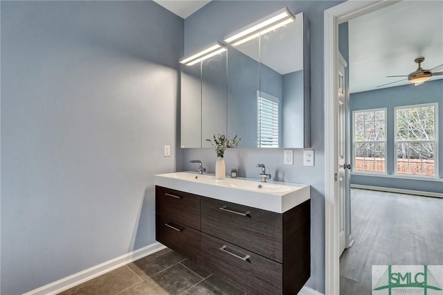 bathroom with double vanity, a ceiling fan, a sink, tile patterned flooring, and baseboards