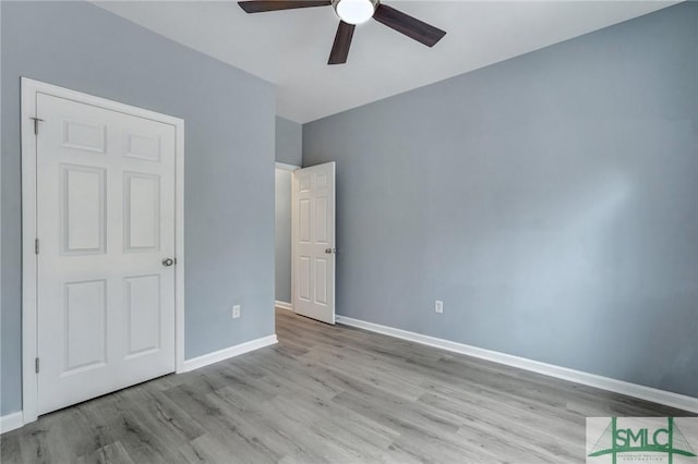 unfurnished bedroom with light wood finished floors, a ceiling fan, and baseboards