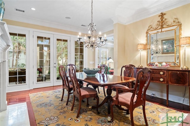 dining space with an inviting chandelier, visible vents, ornamental molding, and wood finished floors