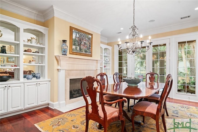 dining room featuring crown molding, a fireplace, visible vents, and wood finished floors