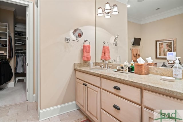 bathroom with tile patterned flooring, vanity, baseboards, a spacious closet, and ornamental molding