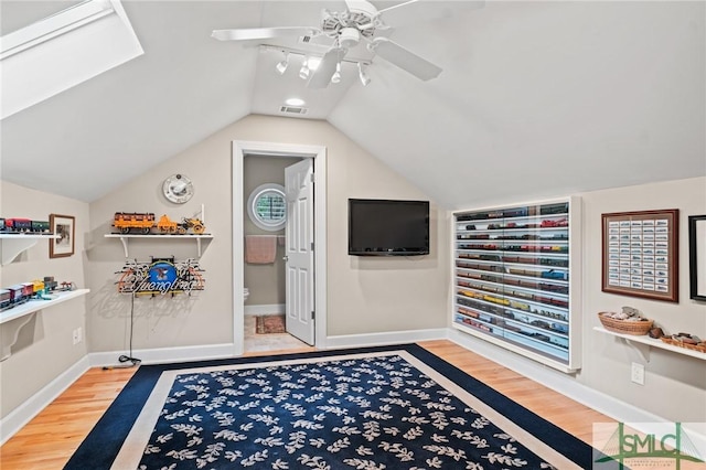 interior space featuring lofted ceiling, a ceiling fan, visible vents, and wood finished floors