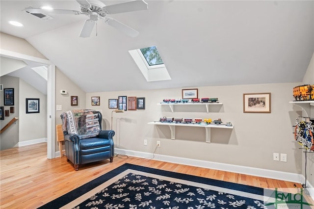 sitting room with light wood-style floors, baseboards, and lofted ceiling with skylight