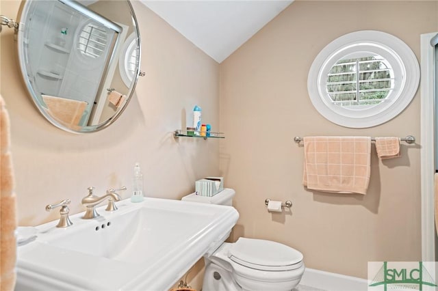 bathroom featuring lofted ceiling, toilet, a sink, baseboards, and an enclosed shower