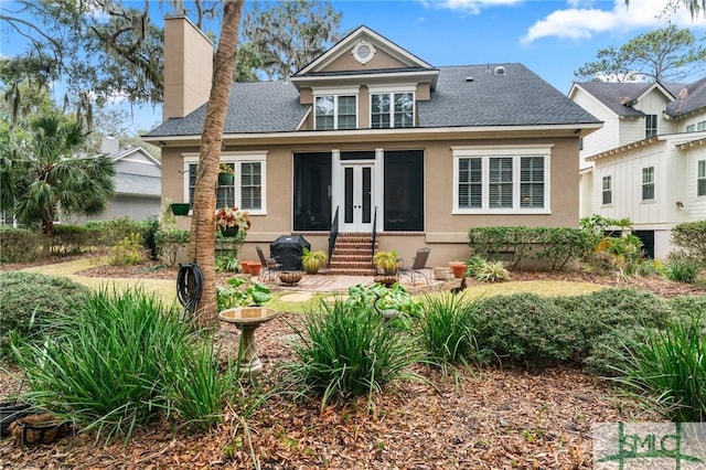 back of house featuring french doors, a chimney, stucco siding, a shingled roof, and entry steps