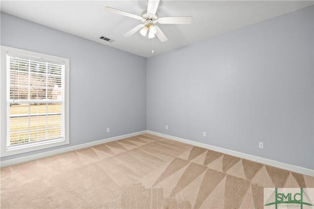 carpeted empty room with baseboards, visible vents, and a ceiling fan