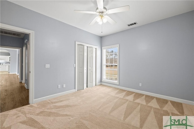 unfurnished bedroom with carpet, visible vents, arched walkways, and baseboards