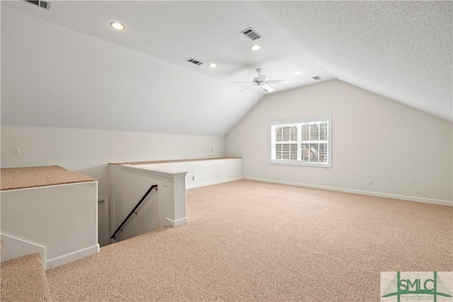 bonus room with lofted ceiling, visible vents, a textured ceiling, and light colored carpet