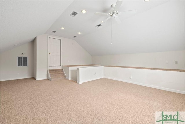 additional living space with light carpet, visible vents, and vaulted ceiling