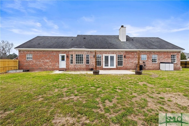 rear view of house with a yard, a patio area, brick siding, and fence