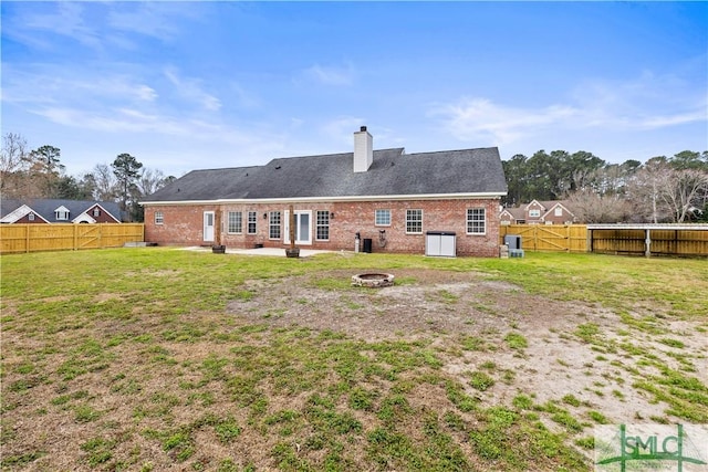 back of house with a yard, a chimney, an outdoor fire pit, a gate, and a fenced backyard