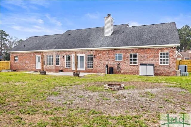 back of property featuring a chimney, a fire pit, fence, and brick siding