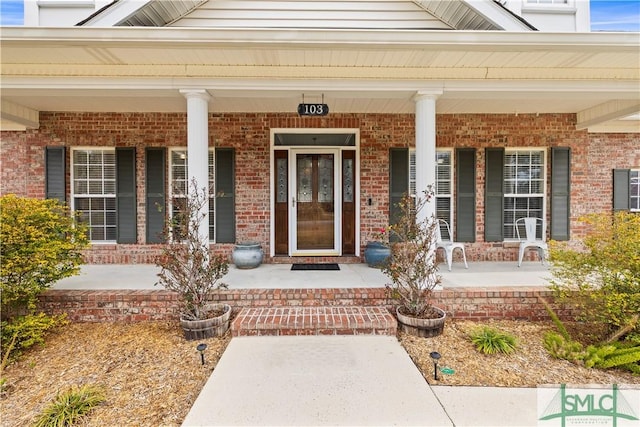 entrance to property featuring covered porch and brick siding