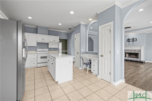 kitchen with white cabinetry, light countertops, white range with electric stovetop, a center island, and stainless steel fridge