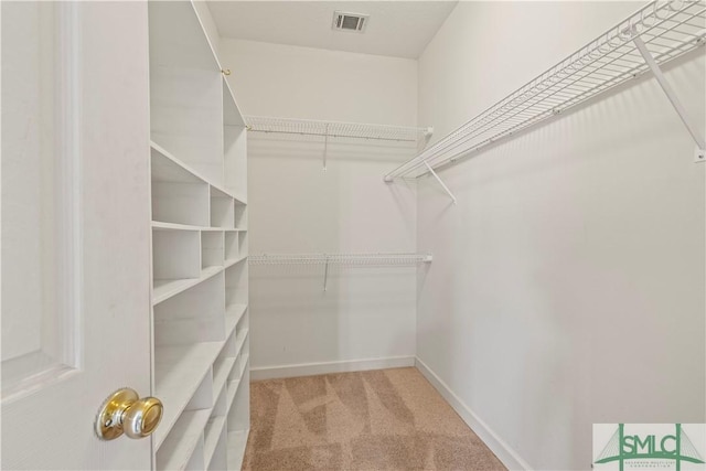 walk in closet with visible vents and light colored carpet