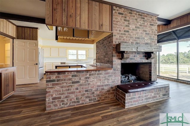 kitchen featuring dark wood-style flooring, a fireplace, a sink, and freestanding refrigerator