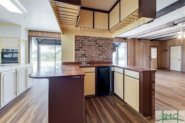 kitchen with dark wood-style floors, black oven, a sink, and fridge