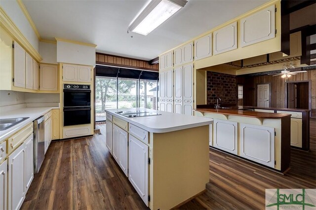 kitchen featuring a sink, a kitchen island, light countertops, dark wood-style floors, and black appliances