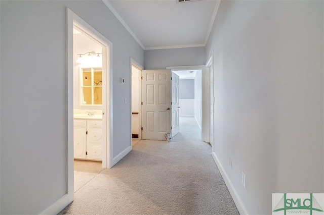 corridor featuring light carpet, ornamental molding, visible vents, and baseboards