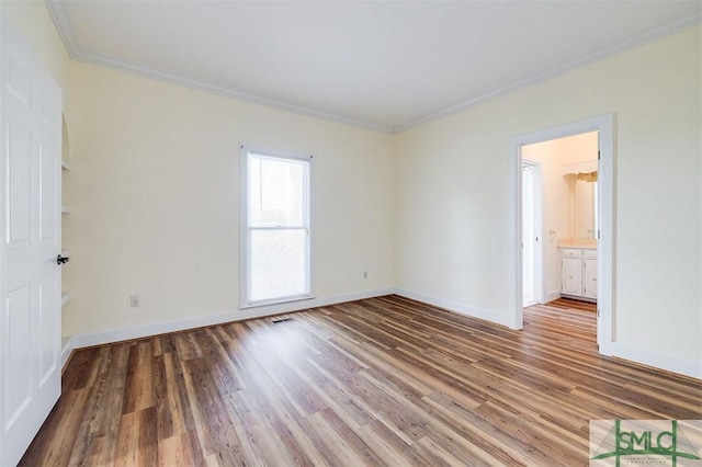 unfurnished room featuring ornamental molding, baseboards, and wood finished floors