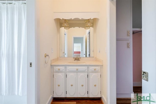 bathroom with wood finished floors, vanity, and baseboards