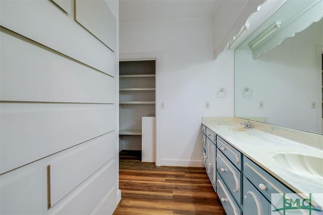 full bath featuring double vanity, baseboards, a sink, and wood finished floors