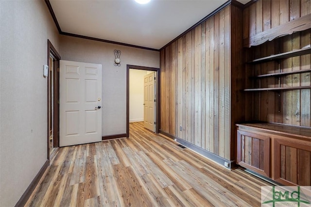 empty room featuring ornamental molding, visible vents, light wood-style flooring, and baseboards