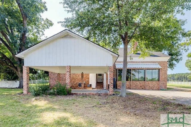 back of house featuring brick siding, fence, and a lawn