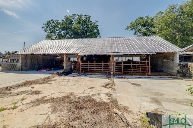 view of front of home featuring metal roof, concrete driveway, an outdoor structure, and an exterior structure