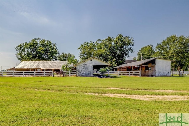 view of yard featuring a rural view, an outdoor structure, and an exterior structure