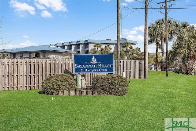 community sign with fence and a yard