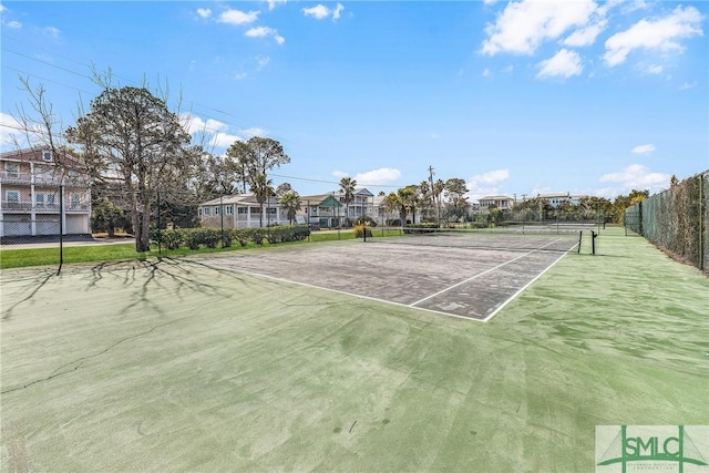 view of tennis court with fence and a residential view