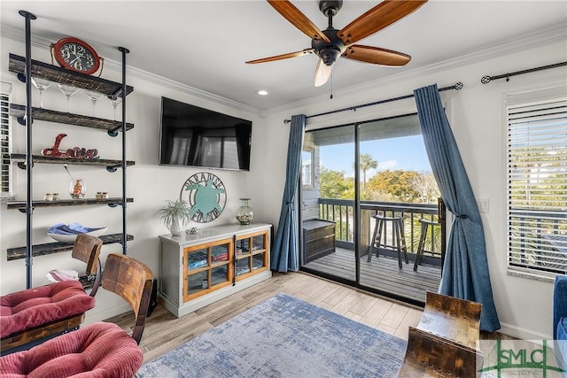 living area with baseboards, ceiling fan, ornamental molding, and light wood-style floors