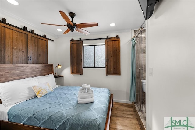 bedroom with light wood finished floors, a barn door, baseboards, a ceiling fan, and recessed lighting