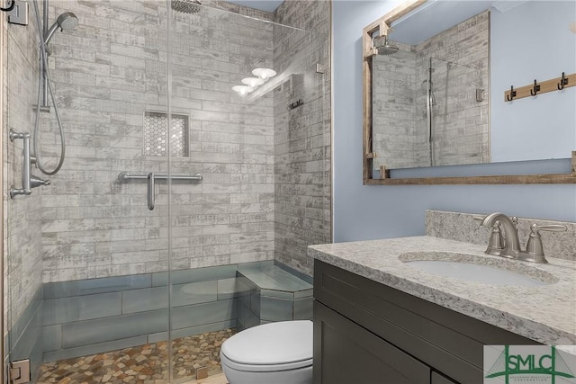 bathroom featuring a shower stall, toilet, and vanity