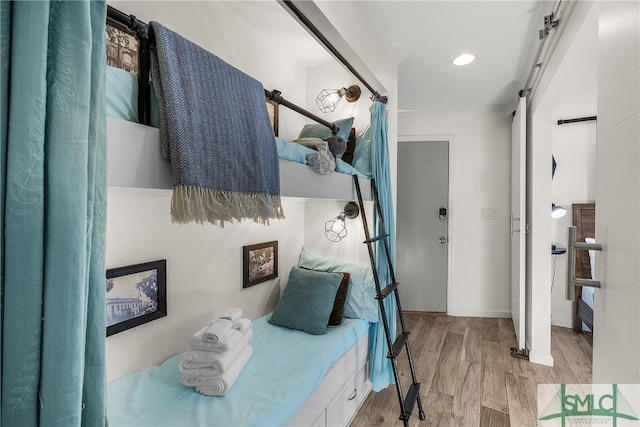 bedroom with a barn door and light wood-style floors