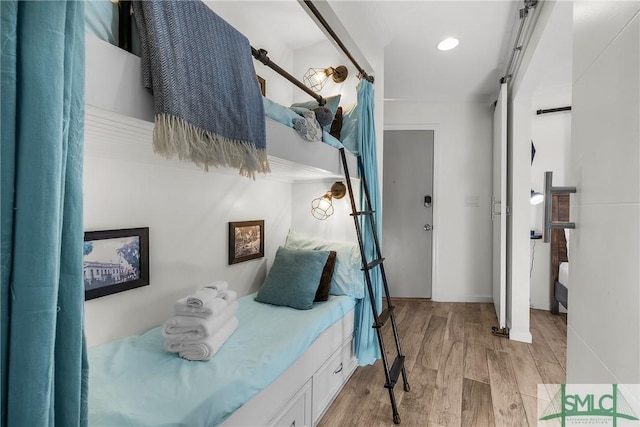 bedroom featuring light wood-style floors and a barn door