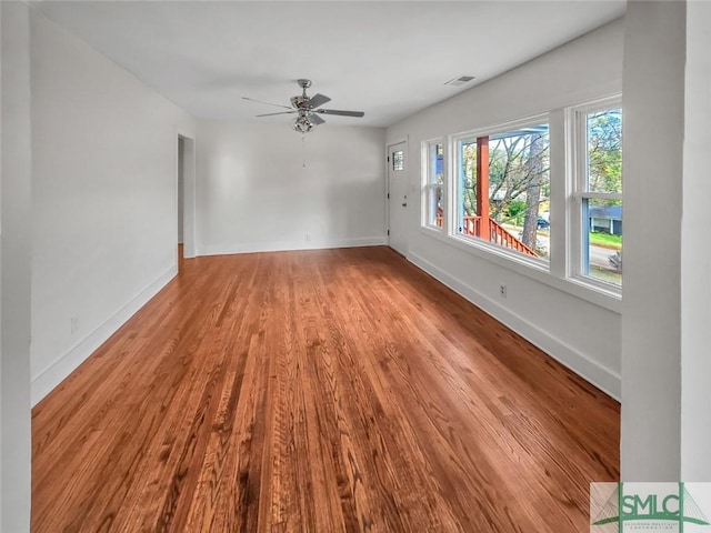 interior space featuring light wood-style floors, a ceiling fan, visible vents, and baseboards