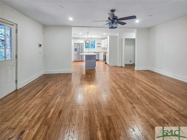 unfurnished living room featuring ceiling fan, recessed lighting, wood finished floors, and baseboards