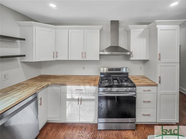 kitchen with wall chimney exhaust hood, butcher block countertops, white cabinetry, and stainless steel appliances