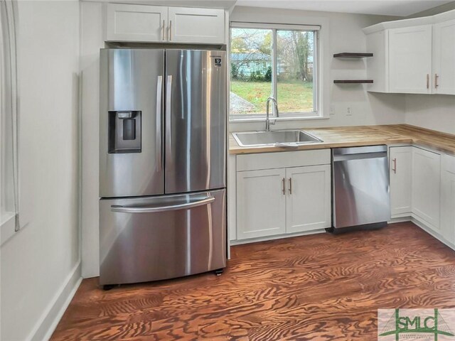 kitchen featuring wood counters, stainless steel appliances, white cabinetry, open shelves, and a sink