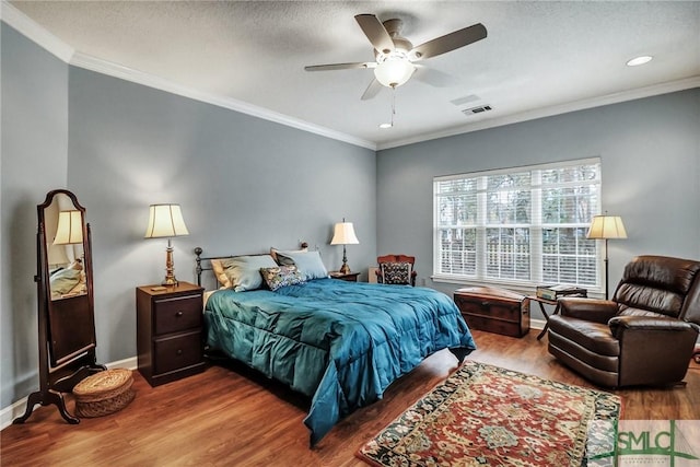 bedroom featuring ornamental molding, a textured ceiling, baseboards, and wood finished floors