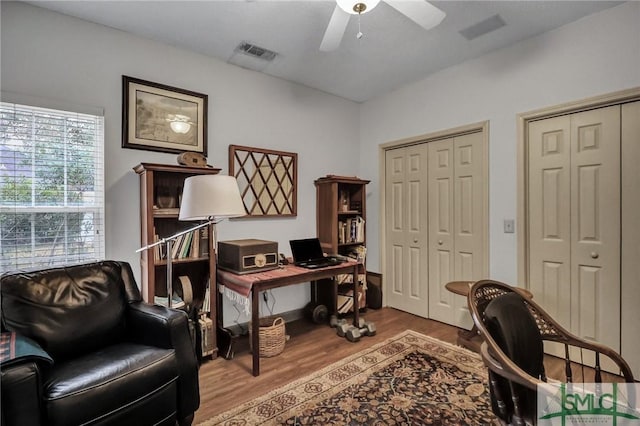 home office with visible vents, ceiling fan, and wood finished floors